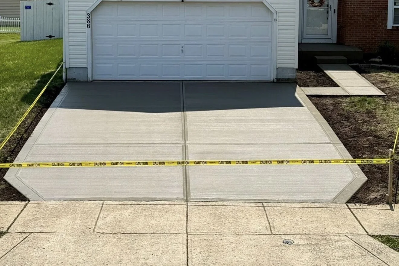 White two-story house with a double garage and arched window, caution tape across the driveway in front of the home